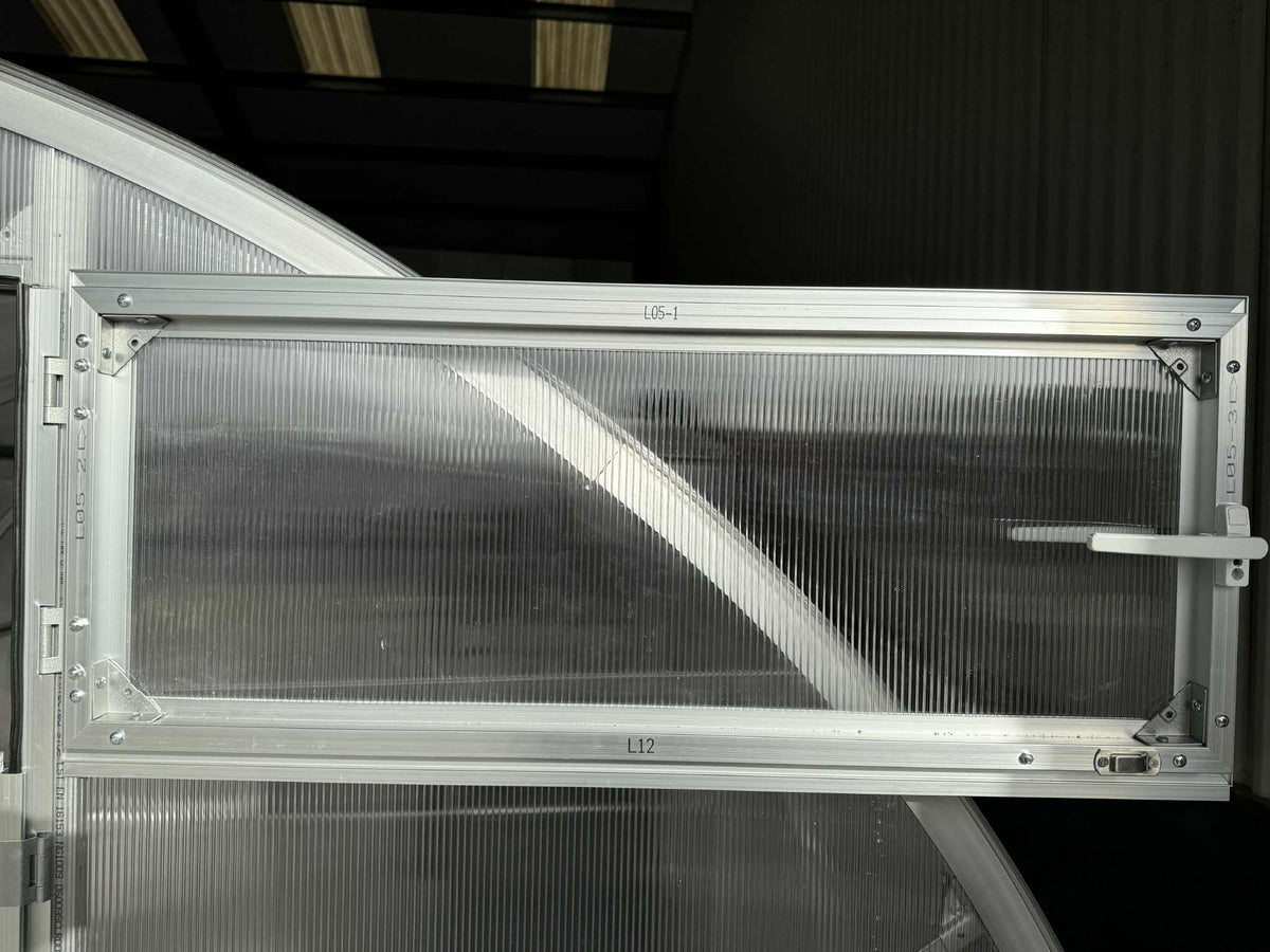 Metallic window of a Sigma 300 (Gen III) greenhouse with visible branding on a dark background