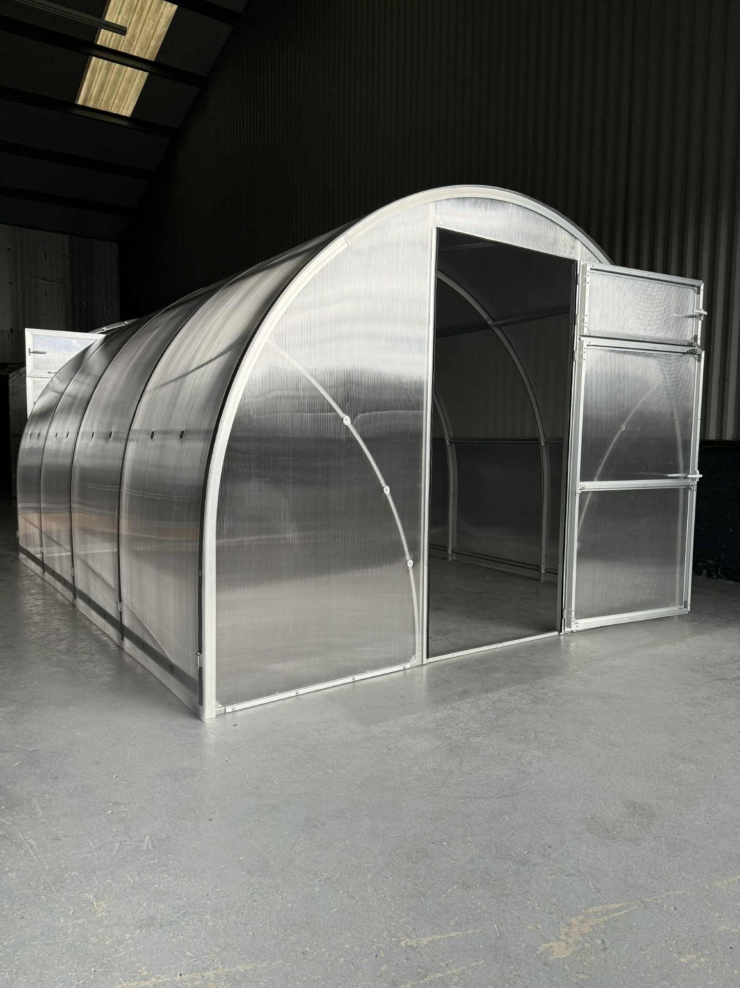 Longitudinal view of a large  Sigma 300 (Gen III) greenhouse with a metallic frame inside a warehouse.