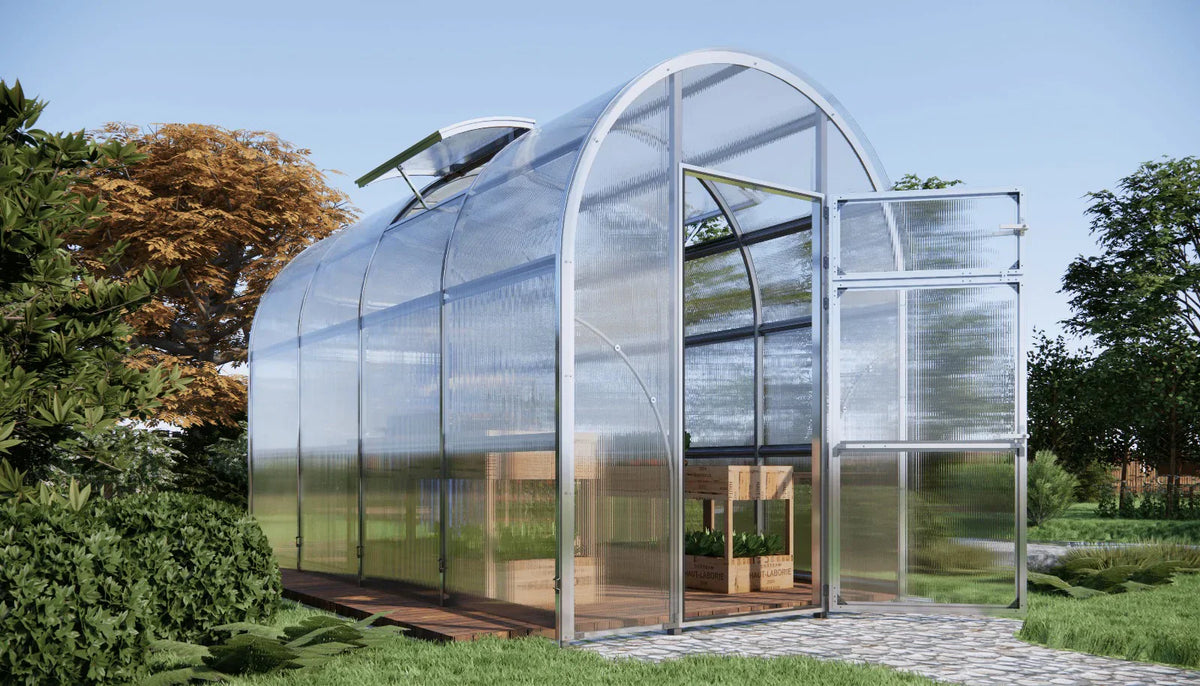 Modern Sigma 200 (Gen III) greenhouse with transparent walls and a curved roof in a garden setting - by Planta Greenhouses EU.