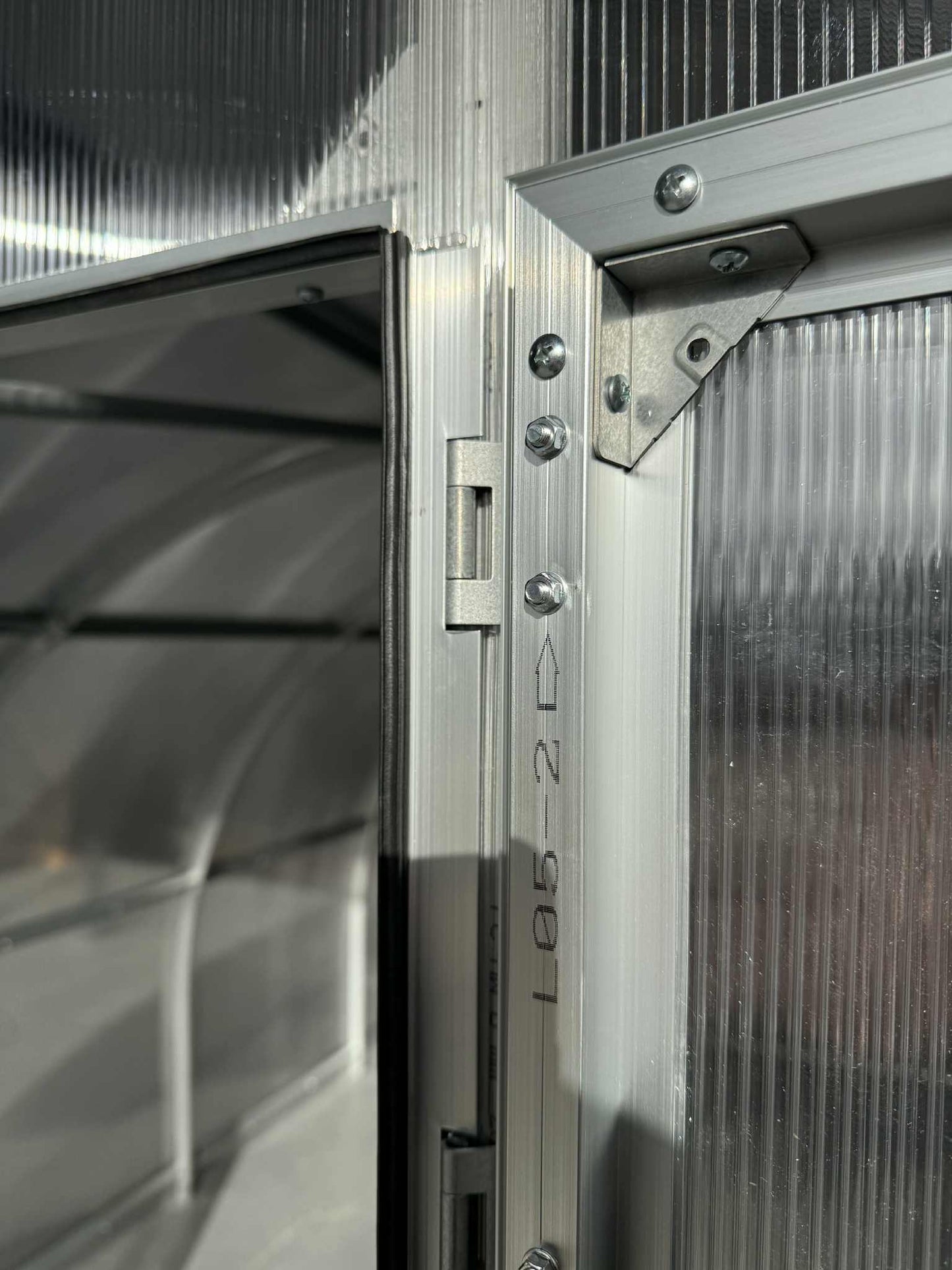 Close-up of a metallic door hinge of a Sigma 300 (Gen III) greenhouse.