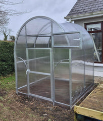 Small Sigma 2x4 (Gen III) greenhouse on a garden with a house in the background
